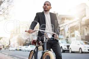 Traveling with the environment in mind. a handsome young businessman pushing his bicycle during his morning commute into work.