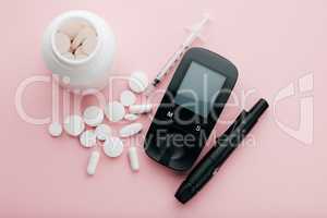 Keeping my diabetes under wraps. High angle shot of a blood glucose meter and pills in an empty studio.