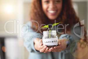 Young african american woman presenting her glass savings jar with a budding plant growing out from it at home. Happy mixed race person smiling while planning, saving and investing for her future