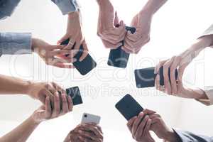 There is more power in unity than division. a group of businesspeople using their phones in synchronicity.