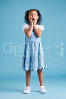 Adorable hispanic little girl with hands on face and mouth open being surprised and shocked showing true astonished reaction against a blue studio background