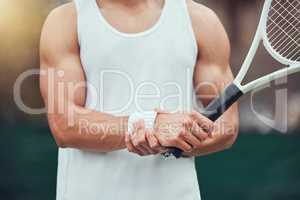 One unknown mixed race tennis player suffering from wrist injury in court game. Hispanic fit professional in pain while holding and rubbing hand after match. Sporty man holding racket in sports club