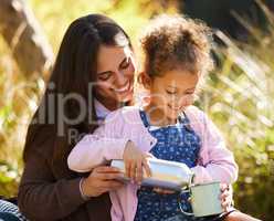 I can pour. an adorable little girl pouring her mother coffee from a flask during their picnic in the park.