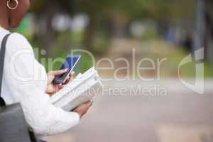 At campus, see you in a bit. a woman using a smartphone outside at college.