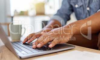 Closeup of a mans hand typing an email while working on a laptop alone at home. One person using a laptop on a table in the lounge at home
