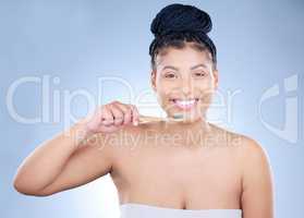 Polish with pride. Studio portrait of an attractive young woman brushing her teeth against a blue background.