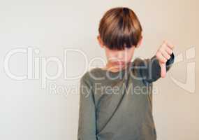 He has to grow into his sense of humour. Studio shot of a cute little boy showing the thumbs down against a wall.