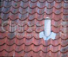 Closeup of red brick chimney chute against blue sky with clouds for combustion gas or home insulation on tiled roof. Architecture design on house building for smoke extraction from fireplace furnace