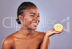 I have a natural beauty remedy for you. Studio shot of a beautiful young woman holding a halved lemon.