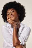 Studio portrait of a young stunning African American woman with a beautiful afro. Confident black female model showing her smooth complexion and natural beauty while posing against a grey background