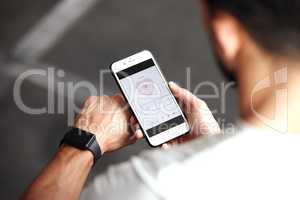Closeup of one mixed race man checking health applications on digital wristwatch and cellphone for exercise in a gym. Guy from above wearing fitness tracker on arm and reading data about heart rate, body temperature and blood pressure on a phone screen