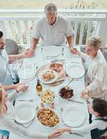 Bless the food before us. Shot of a beautiful family blessing the food with a prayer at the table together at home.