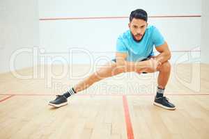 Full length of squash player stretching and looking focused before playing court game with copyspace. Fit active hispanic athlete standing alone and getting ready for training practice in sports centre