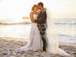 I pledge to honour you, love you and cherish you. Shot of a young couple on the beach on their wedding day.