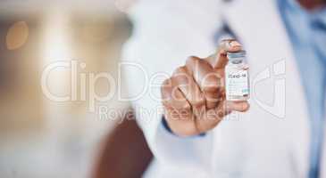 Closeup hand of african american woman doctor holding a bottle of the corona virus vaccine while standing in her hospital office. Be safe during the pandemic outbreak. Stop the spread of covid 19