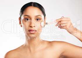 Give your face a little massage. Studio portrait of an attractive young woman using a face roller against a grey background.