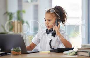 Let me find that for you. an adorable little girl dressed as a businessperson sitting in an office and using a laptop and telephone.