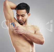 Too much body hair causes bad body odour. Cropped studio shot of a muscular young man shaving his armpit against a grey background.