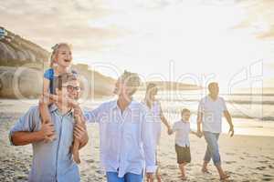 Multi generation family holding hands and walking along the beach together. Caucasian family with two children, two parents and grandparents enjoying summer vacation