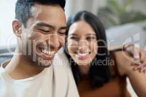 I live to see this man smile. a young couple sitting together in their living room at home and bonding.