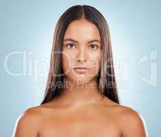 Portrait of a hispanic brunette woman with long lush beautiful hair posing against a grey studio background. Mixed race female standing showing her beautiful healthy hair
