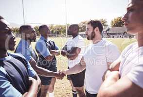 Two opponent rugby teams shaking hands before or after a match outside on a field. Rugby players sharing a handshake to show respect and sportsmanship. A mutual understanding for the game to be played