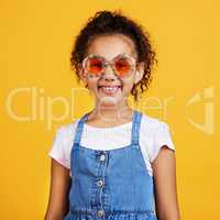 Studio portrait mixed race girl wearing funky sunglasses Isolated against a yellow background. Cute hispanic child posing inside. Happy and carefree kid with an imagination for being a fashion model