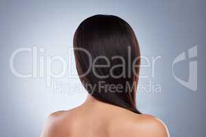 Rear view of brunette woman posing with her hair over her shoulder. Young mixed race woman with healthy smooth straight hair