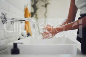 Close up of female hands using soap and washing hands under faucet with clean water. Woman rubbing hands together before rinsing for coronavirus prevention
