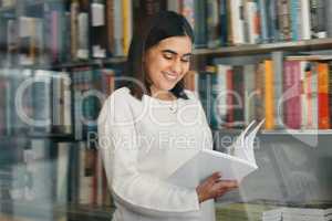 One of the best libraries. a young female student reading a book in her school library.