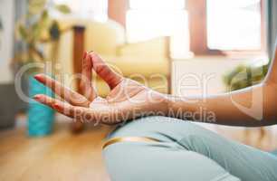 Maintaining peace of mind and body. Closeup shot of an unrecognisable woman meditating at home.