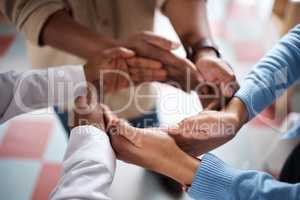 Unity is necessary to achieve your vision. Shot of a group of businesspeople joining hands in solidarity in a modern office.