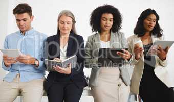 Group of serious diverse businesspeople standing and using digital tablets and writing in notebooks together in an office. Content business professionals working and planning at work