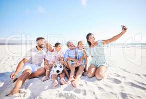 Multi ethnic family taking a selfie to capture and document beautiful moments together. Family with two children, two parents and grandparents on a video call while playing soccer on the beach