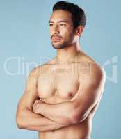 Handsome young hispanic man standing shirtless in studio isolated against a blue background. Mixed race topless male athlete looking confident, healthy and fit. Exercising to increase his strength