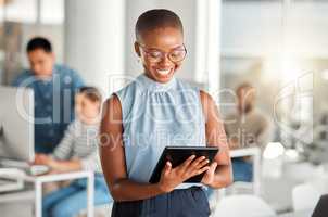 Cheerful african american businesswoman working on a digital tablet at work. Joyful black female businessperson using social media on a digital tablet. Businessperson checking an email on a digital tablet