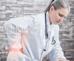 My health is not what it used to be. Shot of a mature doctor experiencing lower back pain while working in a medical office.