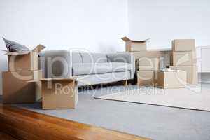 Time to unpack. Shot of cardboard boxes and a sofa in an empty living room during the day.