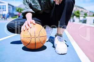 Unrecognizable person getting ready to enjoy a game of basketball on the court outside. Unrecognizable basketball player standing on the court with a ball preparing to play