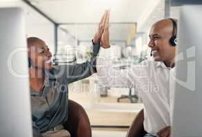 Two happy call centre telemarketing agents giving each other high five and cheering with joy while working in an office. Excited and ambitious consultants celebrating successful sales targets and winning victory