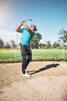 I have to get out of this sand bank. a focused young male golfer about to swing and play a shot with his golf club outside on a course.