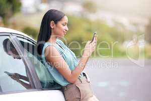 Woman leaning on a car texting. Businesswoman using a cellphone to scroll online. Businesswoman texting vehicle repair service. Businesswoman broken car. Businesswoman standing by car using smartphone