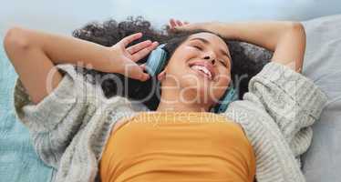 Let the rhythm flow through you. a young woman lying down and enjoying the music.