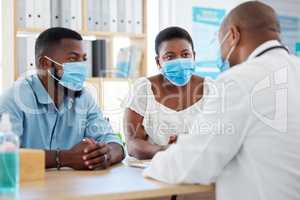African american married couple in consult for fertility treatment. Medical doctor talking to a couple about ivf treatment. Prenatal specialist in a checkup with a couple wearing covid masks