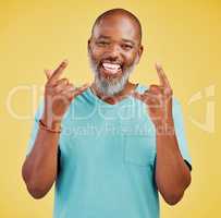 Portrait of a mature friendly african american man looking happy and smiling while making an rock on hand gesture against a yellow studio background. Expressing that you need to To party to rock music. An expression of celebration