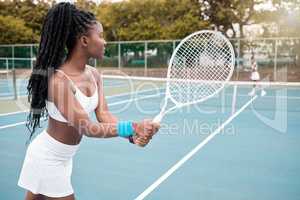 Young athlete waiting to serve during a tennis match. Focused african american tennis player during a match. Girl playing tennis with her friend. Sporty woman competing in a tennis match
