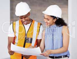 Im pleased with these. Shot of two young contractors standing inside together and looking at building plans.