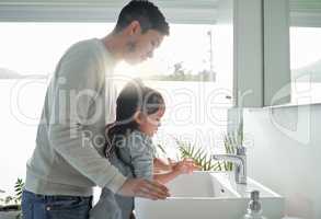 Start them young with personal hygiene. a father helping his daughter wash her hands at a tap in a bathroom at home.