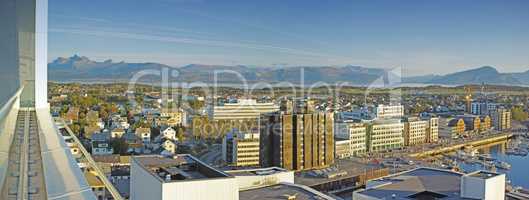 Cityscape view of urban city buildings and infrastructure with background mountains in popular overseas travel destination. Busy downtown centre and urban architecture and blue sky in Bodo, Norway