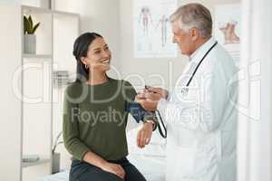 Youre as fit as a fiddle. a senior doctor standing and checking his patients blood pressure during a consultation in the clinic.